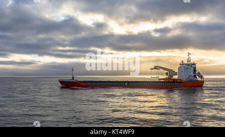 Frachtschiff auf der Nordsee unter dramatischen Himmel kurz vor Sonnenuntergang Stockfoto