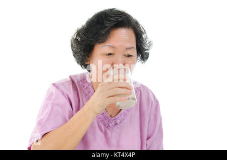 Ältere Frau trinkt Milch mit Glas Stockfoto