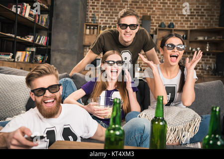 Neugierige junge Freunde in 3D-Brille ansehen Film auf dem Sofa zu Hause Stockfoto