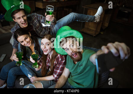 Hohe Betrachtungswinkel von Freunden mit Bier machen selfie am St. Patrick's Day Stockfoto