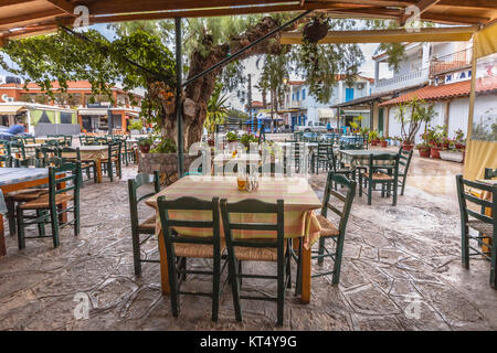 Traditionelles Dorf Restaurant Terrasse mit Holztischen und Stühlen unter einem riesigen Baum Stockfoto