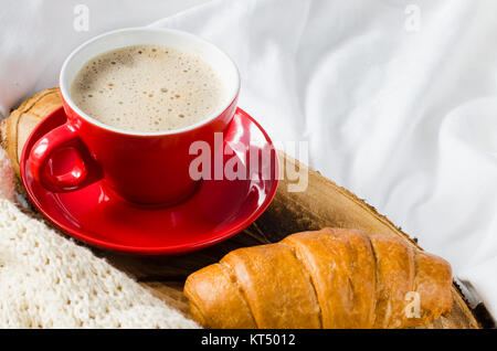 Cappuccino, Schokolade und Croissant auf einem Bett. Stockfoto