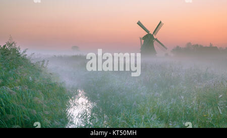 Holländische Polderlandschaft mit charakteristischen traditionelle Windmühle an einem nebligen Septembermorgen in den Niederlanden Stockfoto