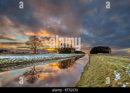 Lowland river canal Tjonger fließt durch flache verschneite Landschaft von Friesland in den Niederlanden Stockfoto