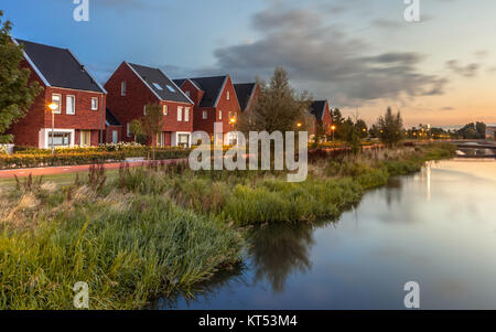 Lange Belichtung Night Shot der Straße mit modernen ökologischen Mittelklasse Familie Häuser mit umweltfreundlichen River Bank in Veenendaal, Niederlande. Stockfoto