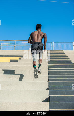 Muskulöse jamaikanische Sportler bis Sprinten plyometric Training im Stadion in Sicht nach hinten. Stockfoto