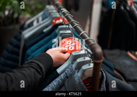 Mann wählt die Kleidung auf Bügeln hängend im Shop Stockfoto