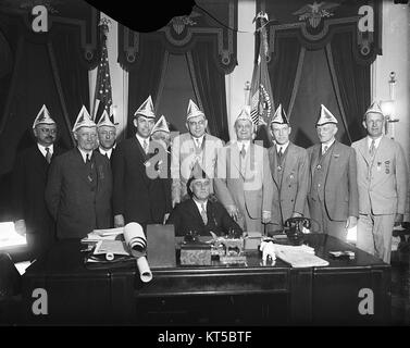 Dieses Foto zeigt Präsident Franklin D. Roosevelt mit einer Gruppe von Einzelpersonen, wahrscheinlich von einem bedeutenden politischen oder historischen Ereignis. Roosevelt, bekannt für seine Führungsrolle während der Weltwirtschaftskrise und des Zweiten Weltkriegs, bleibt eine zentrale Figur in der amerikanischen Geschichte. Stockfoto