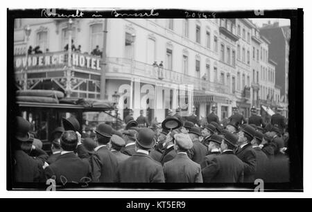 Dieses Bild zeigt die Menge, die sich in Brüssel versammelt hat, um den Besuch von Präsident Franklin D. Roosevelt zu erleben. Der Blick von der Menschenmenge auf den Balkon des Providence Hotels, der einen Moment des frühen 20. Jahrhunderts festnimmt. Stockfoto