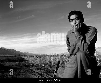 Dieses Foto, das Ansel Adams 1943 aufgenommen hat, zeigt Tom Kobayashi, einen Japaner, der während des Zweiten Weltkriegs im Internierungslager Manzanar inhaftiert war. Adams hat die krasse Realität des Lebens im Lager festgehalten und die menschlichen Kosten der Kriegspolitik für Japaner hervorgehoben. Stockfoto