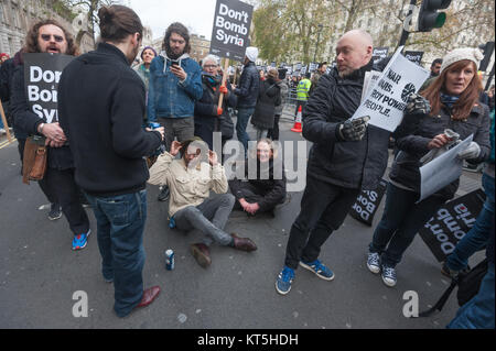 Keine Bombe Syrien Demonstranten stehen und sitzen auf Whitehall Datenverkehr zu blockieren, ignorieren Polizei fordert von der Straße zu bekommen. Stockfoto