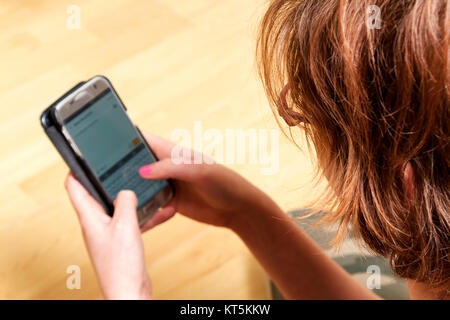 Eine junge Frau schreibt Nachrichten auf ihr Mobiltelefon Stockfoto