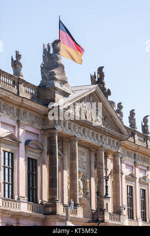 Giebelrelief und Balustradenplastiken über dem Hauptportal des Zeughauses in Berlin mit der Deutschlandfahne Stockfoto