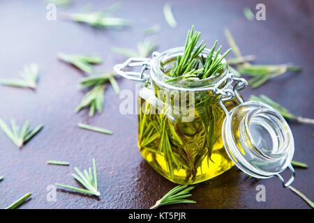 Rosmarin Öl. Rosemary wesentliches öl Glas Glas Flasche und Zweige der Pflanze Rosmarin mit Blumen auf rustikalen Hintergrund Stockfoto