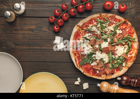 Blick von oben auf die italienische Pizza, Cherry tometoes und leere Teller auf hölzernen talbetop Stockfoto