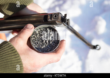 Ein Mann in einem Camouflage Jacke mit einem bb Gewehr und ein Feld von buckshot, Munition. Stockfoto