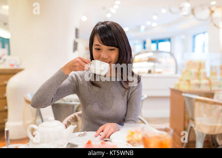 Frau trinkt Kaffee in Cake Shop Stockfoto