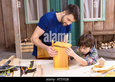 Vater und Sohn machen Holz Vogelhaus zusammen konzentriert Stockfoto