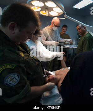 Commander Carlos Marco, Manaus Naval Poliklinik Direktor (links), Komfort, um einen 14-jährigen einheimischen Jungen an Bord NAsH Soares de Meirelles auf dem Amazonas in Brasilien, am 27. November. Lt.Cmdr. Thomas Barlow, ein US-Marine Arzt (3. von links), und 1. Lt Priscila Tomy Ribeiro, einer brasilianischen Medical Officer (2. von links), reinigen Sie die Schussverletzung in die Hand des Jungen. Nach der Verletzung, die Familie des Jungen hatte NAsH Soares de Meirelles, die vorbei war entlang des Flusses gefeiert, und mit einem kleinen Boot verwendet ihn, um das Schiff zu bringen. Barlow ist Mitglied eines Teams von fünf US-Navy Ärzte, die sich in einer m Stockfoto