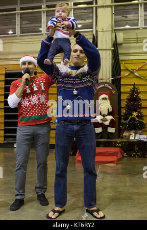 CAMP FOSTER, Okinawa, Japan - ein Vater hält seinen Sohn während der häßlichen Pullover Contest am Hauptsitz und jährliche Holiday Party's Support Battalion Dez. 5 am Foster Fieldhouse an Bord Camp Foster, Okinawa, Japan. Marines nahm hässliche Pullover und Pie essen Wettbewerbe. Die Teilnehmer hatten die Chance, Preise durch eine Verlosung während der Veranstaltung zu gewinnen. Die Partei brachte Marines und ihren Familien heraus für eine Nacht des festlichen Spaß. (U.S. Marine Corps Stockfoto