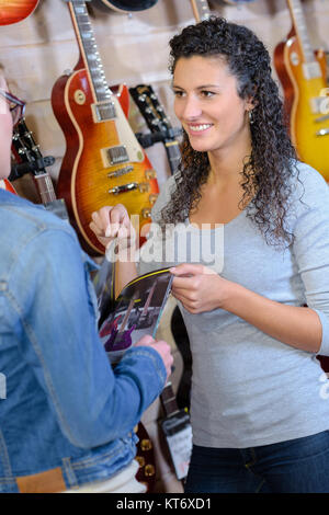 Weibliche Kunden, die auf der Suche nach neuen Gitarre im Laden und lächelnd Stockfoto