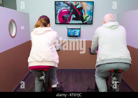 Älterer Mann und Frau Spinnen auf Fitness Bikes Stockfoto