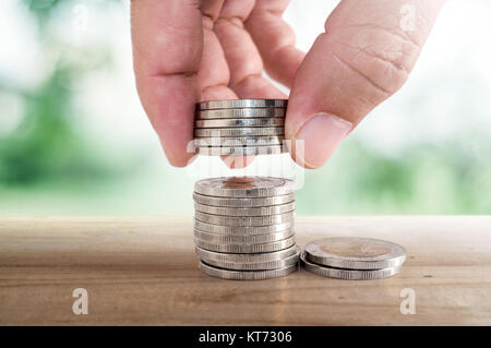 Geld sparen Konzept. Hand Münze zu Stapeln von Münzen. Stockfoto