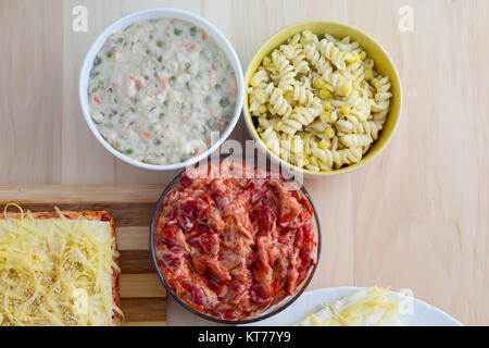 Bunte Salate in Keramikschalen und Salzkuchen mit Käse und rote paprika Stockfoto