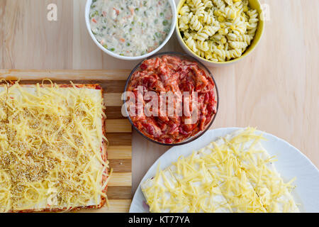 Bunte Salate in Keramikschalen und Salzkuchen mit Käse und rote paprika Stockfoto