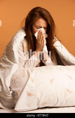 Krankheit Grippe - junge Frau auf dem Bett liegend angesteckt mit Allergie blasen Ihre Nase Stockfoto