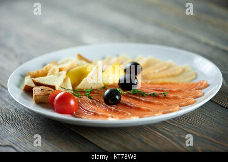 In der Nähe von weißen Platte mit den delicios Vorspeisen: frische Tomaten, schwarze Oliven, weißes Brot, geräuchertem Lachs und Käse. Stockfoto