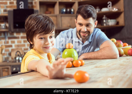 Gerne Vater und Sohn spielen mit Zitrusfrüchten in der Küche Stockfoto