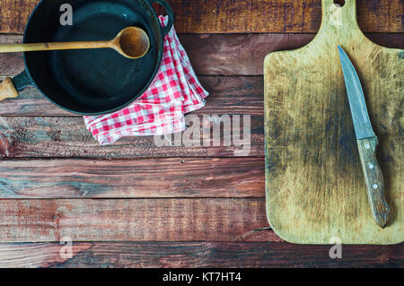 Schwarzen gusseisernen Pfanne und Schneidbrett auf braunem Holz- Oberfläche Stockfoto