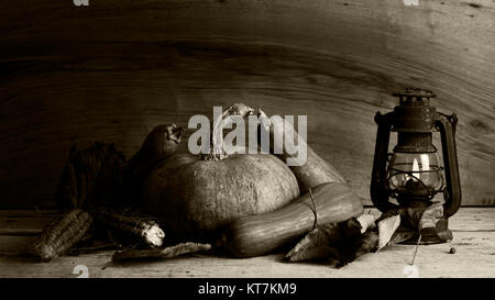 Kürbisse, Maiskolben und Herbst Blätter Dekoration auf einem Holztisch mit alte rostige Laterne Stockfoto