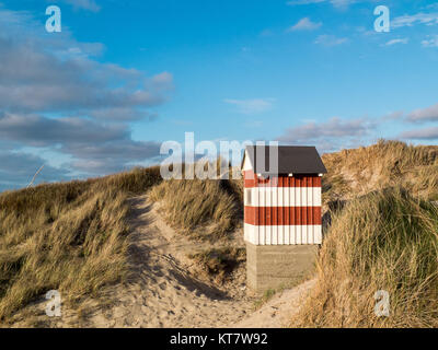 Kleine rot-weiß gestreiften Hütte stehend auf den Strand Dünen mit Blick aufs Meer Stockfoto