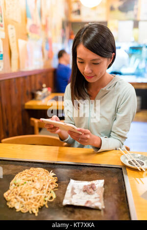 Frau unter Foto auf Okonomiyaki im Japanischen Restaurant Stockfoto