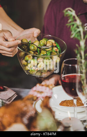 Frau putting Rosenkohl auf Platte Stockfoto