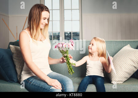 Muttertag. Frau und Kind mit Blumen und Gift Card. Lächelnd Tochter und Mutter Stockfoto