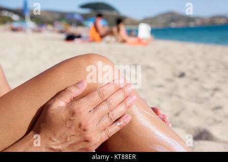 Nahaufnahme eines jungen kaukasischen Mann am Strand Sonnencreme auftragen, um seine Beine rasiert Stockfoto