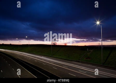 Lange Belichtung geschossen bei Sonnenuntergang leichte Wanderwege aus dem Scheinwerfer und Rücklichter von Autos entlang der M62 in der Nähe von Brighouse fahren in West Yorkshire Stockfoto