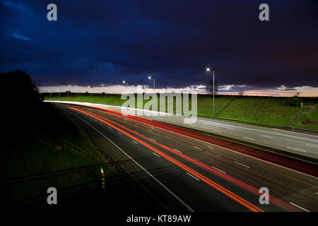 Lange Belichtung geschossen bei Sonnenuntergang leichte Wanderwege aus dem Scheinwerfer und Rücklichter von Autos entlang der M62 in der Nähe von Brighouse fahren in West Yorkshire Stockfoto