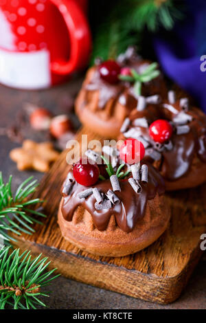 Weihnachten Schokolade Kuchen dekoriert mit Schokoladenüberzug, Rosmarin und Cranberry. Detailansicht, selektiver Fokus Stockfoto