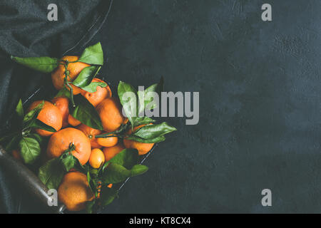 Frische clementinen oder Mandarinen in Korb auf dunklem Stein Hintergrund. Ansicht von oben, kopieren Platz für Text, Bild Stockfoto