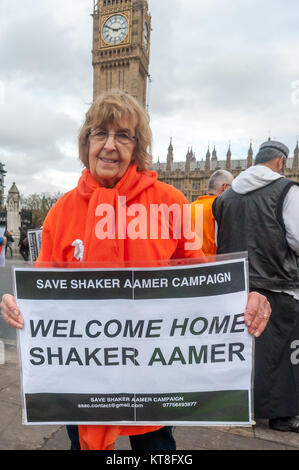 Speichern Shaker Aamer Kampagne Stuhl Freude Hurcombe hält ein Plakat: "Willkommen zuhause, Shaker Aamer' an Ihre Feier seiner Freigabe gegenüber Parlament, wo die Gruppe eine wöchentliche Mahnwache für seine relese gehalten haben. Stockfoto