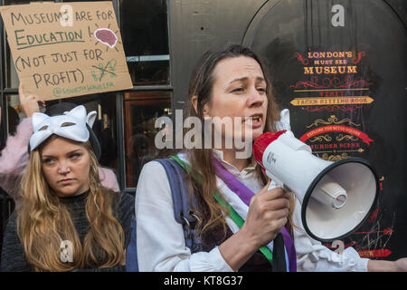 Eine Frau mit reißzähne 'Dracula-' und eine Suffragette Schärpe spricht an der vierten Welle LFA Protest gegen Ripper useum' in Kabel St nach makabren und sehr frauenfeindlich Halloween Werbung. Stockfoto