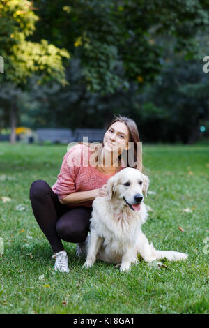 Bild von Mädchen umarmt Hund auf dem grünen Rasen im Frühling Park. Stockfoto