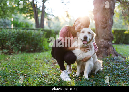 Foto von Frau umarmen Hund auf Rasen im Sommer Park Stockfoto