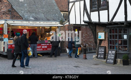 Kunden kaufen Street Food & Menschen mit Tüten durch Shambles Markt, ein historischer Markt in York, North Yorkshire, England, UK. Stockfoto