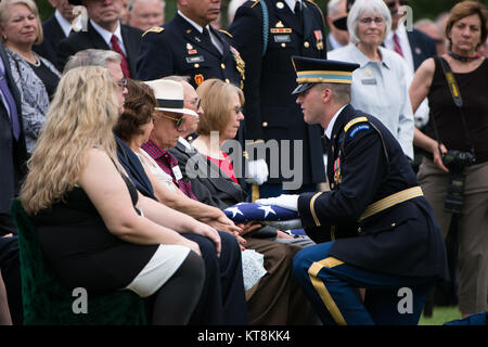 Us-Armee Kapitän Carson Filipowski, rechts, stellt eine amerikanische Flagge zu Peter Ramos, Halbbruder auf US-Army Chief Warrant Officer 3 Rainer S. Ramos, während einer graveside Service in Abschnitt 60 von Arlington National Cemetery, 17. Juni 2015 in Arlington, Virginia. Vier Soldaten, U.S. Army Chief Warrant Officer 3 James L. Phipps, Chief Warrant Officer 3 Rainer S. Ramos, Staff Sgt. Warren Newton und SPC. Fred J. Secrist, hatte fehlende während des Vietnam Krieges gegangen und waren als Gruppe in einem Sarg begraben. Nach Angaben des Verteidigungsministeriums, "On Jan. 9, 1968, die Mannschaft war auf einer Mission über Quang Zinn Stockfoto