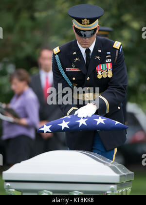 Us-Armee Kapitän Carson Filipowski, 3d-US-Infanterie Regiment (Die Alte Garde), hält eine amerikanische Flagge während einer graveside Service in Abschnitt 60 von Arlington National Cemetery, 17. Juni 2015 in Arlington, Virginia. Vier Soldaten, U.S. Army Chief Warrant Officer 3 James L. Phipps, Chief Warrant Officer 3 Rainer S. Ramos, Staff Sgt. Warren Newton und SPC. Fred J. Secrist, hatte fehlende während des Vietnam Krieges gegangen und waren als Gruppe in einem Sarg begraben. Nach Angaben des Verteidigungsministeriums, "On Jan. 9, 1968, die Mannschaft war auf einer Mission über Quang Zinn (jetzt Teil der Provinz Quang Nam Provinz), Süd Stockfoto